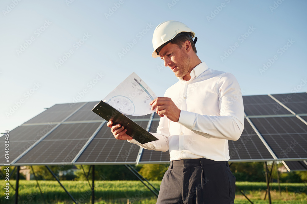 Notepad with document is in hands. Man is doing operating and maintenance in solar power plant Notepad with document is in hands. Man is doing operating and maintenance in solar power plant