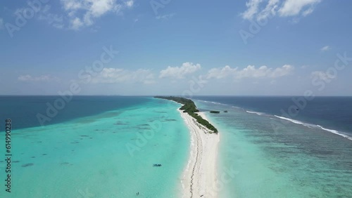 Vast shallow lagoon of turquoise blue clear water surrounding long white sandbar of Dhigurah Island, Maldives. Aerial dolly in photo