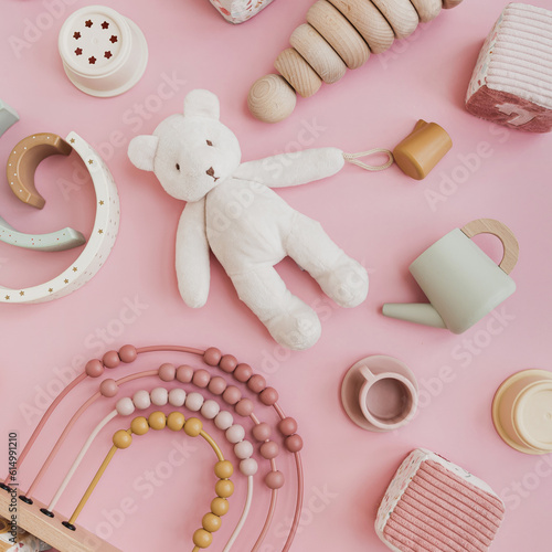 Set of stylish natural Scandinavian baby kids toys on pastel pink background. Baby girl stuff for playing and education. Flat lay, top view photo