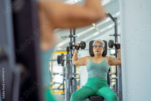 Senior woman doing exercises in the gym to stay healthy, trains muscles.