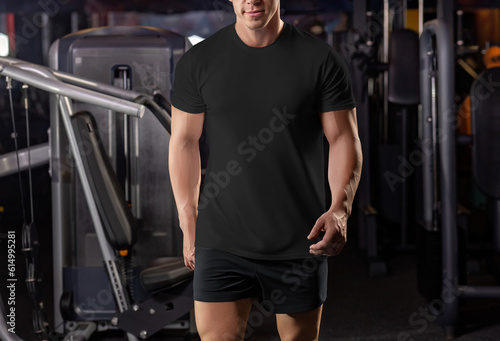 Black t-shirt mockup on a walking muscular man in the gym, from head to knees, sportswear, front view.