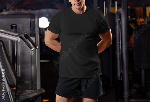 Black t-shirt mockup on a muscular guy with hands behind his back  front view  athlete in the gym  photo from head to knees.