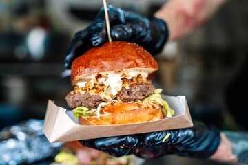 Street food burger on hand on hipster food market background. Grill and barbecue food