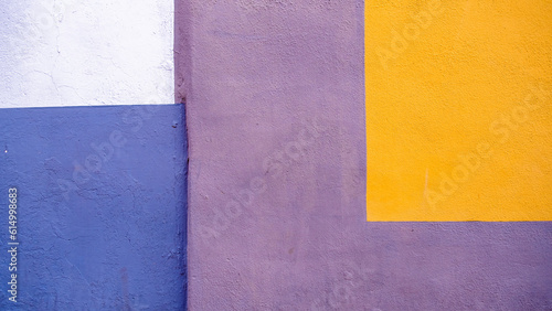 Painted wall textures. Close-up of the wall of a house in purple, yellow, blue and white, forming rectangles that looks like an abstract painting. La Laguna, Tenerife, Canary Islands, Spain