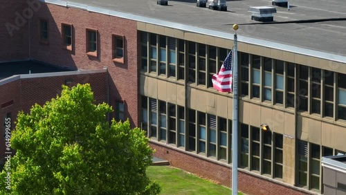 American flag waving in front of USA school. Aerial circling with long zoom lens. photo