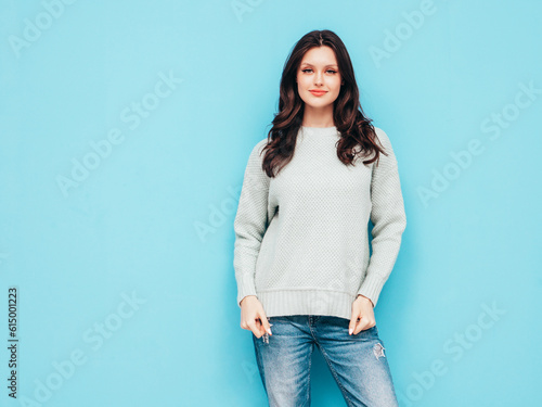 Young beautiful smiling female in trendy summer jeans and sweater clothes. Sexy carefree woman posing near blue wall in studio. Positive model isolated. Cheerful and happy