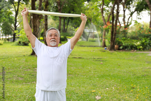 Asian senior man practice yoga excercise, tai chi tranining, stretching and meditation together with towel for relax healthy in park outdoor after retirement. Happy elderly outdoor lifestyle concept