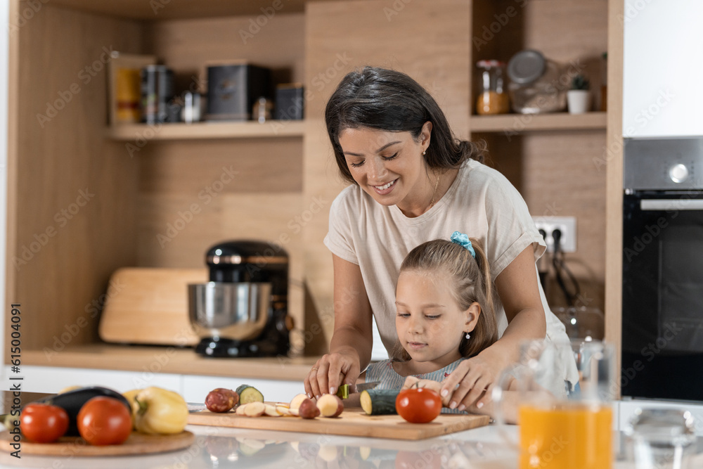 Little girl learning how to cut vegetables and prepare lunch with her mom Little girl learning how to cut vegetables and prepare lunch with her mom