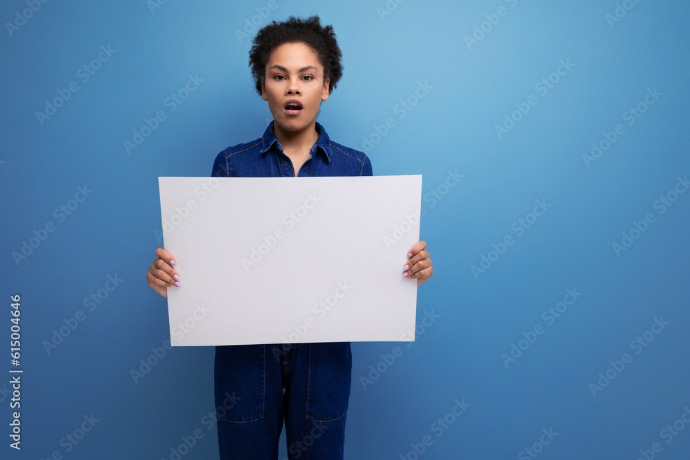 young pretty hispanic business woman with fluffy hair dressed in blue denim suit holding billboard with blank space young pretty hispanic business woman with fluffy hair dressed in blue denim suit holding billboard with blank space