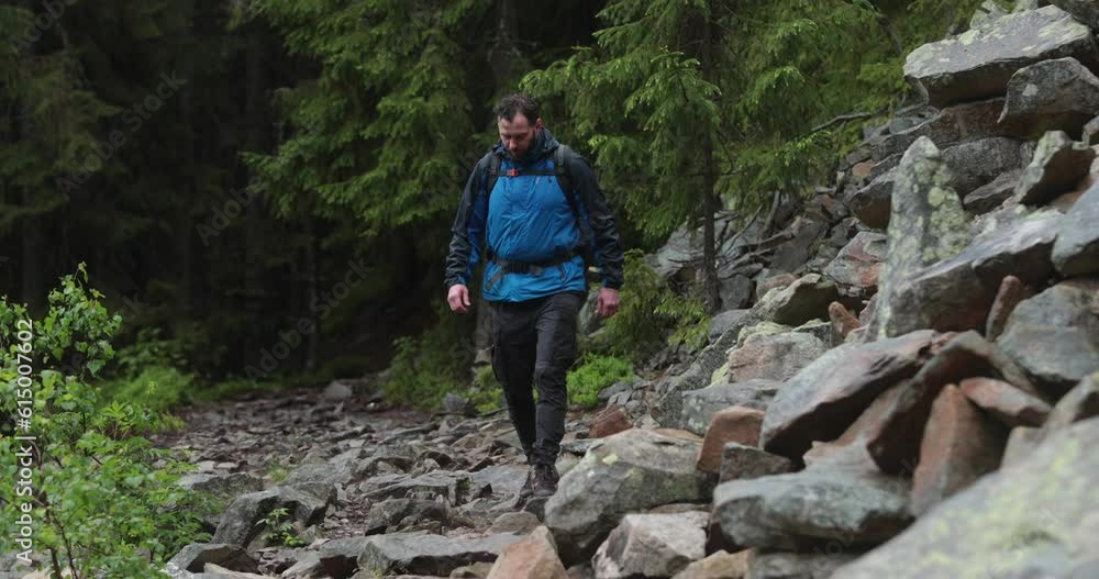 A fit young man is walking alone on a rocky terrain, coming out of the forest. The concept of a man traveling alone. A fit young man is walking alone on a rocky terrain, coming out of the forest. The concept of a man traveling alone.