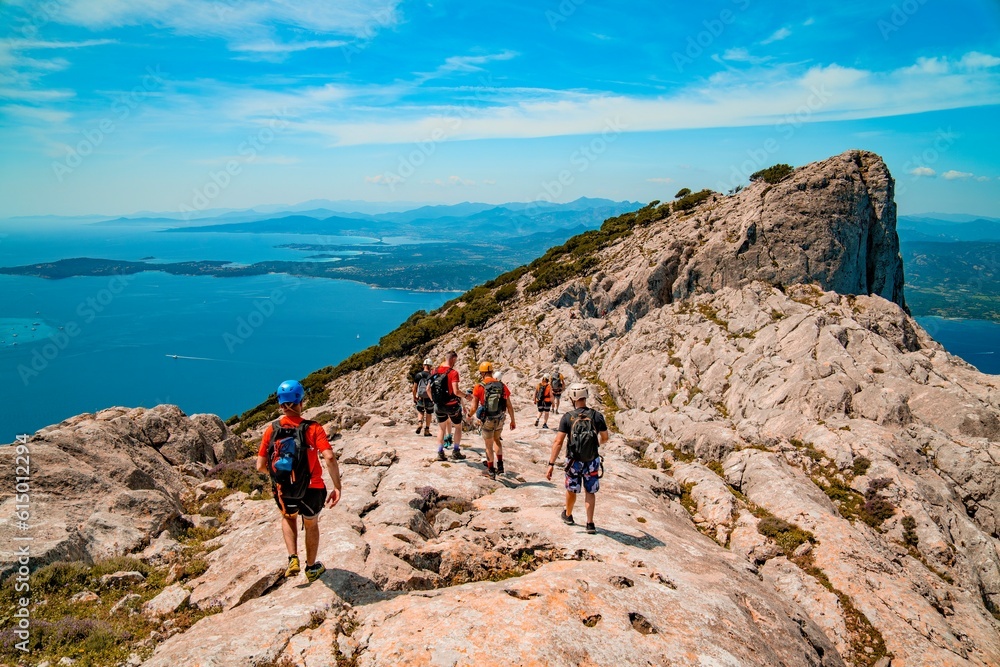 Tourists trek a trail overlooking the Mediterranean Sea