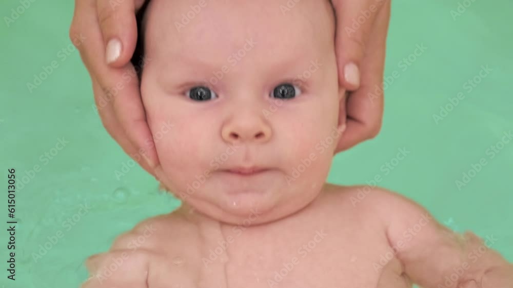 Mom teaches a newborn baby to swim and stay on the water. A two-month-old baby is bathing in a large bathtub. Beautiful newborn baby is washing in the bathroom. Hygiene procedures of a newborn boy. Mom teaches a newborn baby to swim and stay on the water. A two-month-old baby is bathing in a large bathtub. Beautiful newborn baby is washing in the bathroom. Hygiene procedures of a newborn boy.