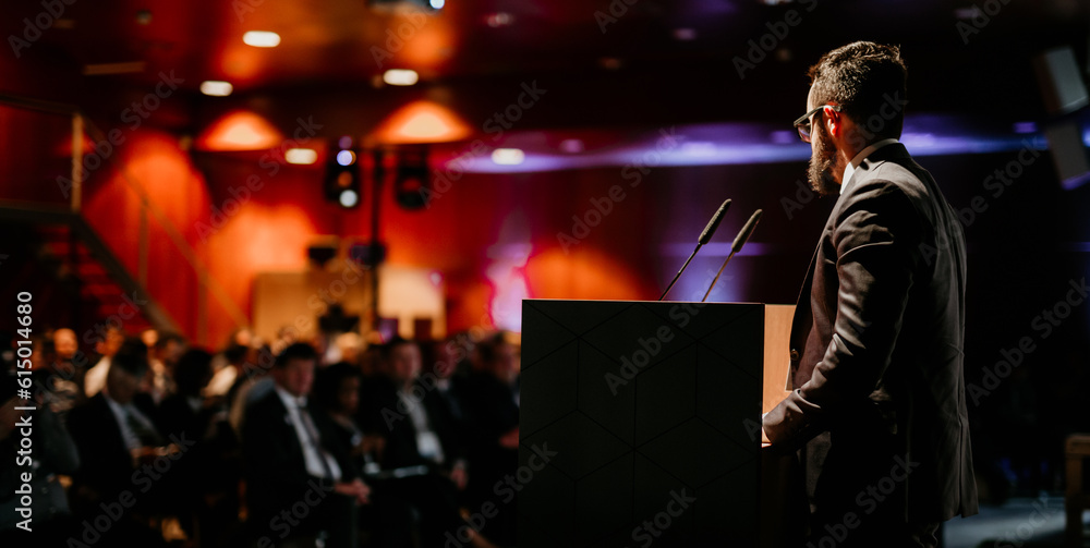 Speaker giving a talk on corporate business conference. Unrecognizable people in audience at conference hall. Business and Entrepreneurship event. Speaker giving a talk on corporate business conference. Unrecognizable people in audience at conference hall. Business and Entrepreneurship event.