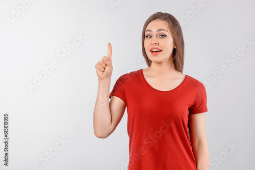 Amused happy cheerful good-looking girl pointing finger up. Winsome female model in red t shirt posing over white studio background. Girl found what you search