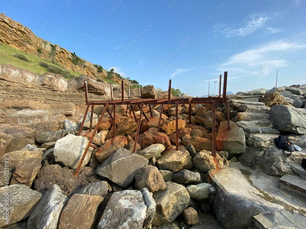 An abandoned rusty pier platform on the cliffs by the sea. Rusty steel beams, remnants of old sea pier An abandoned rusty pier platform on the cliffs by the sea. Rusty steel beams, remnants of old sea pier