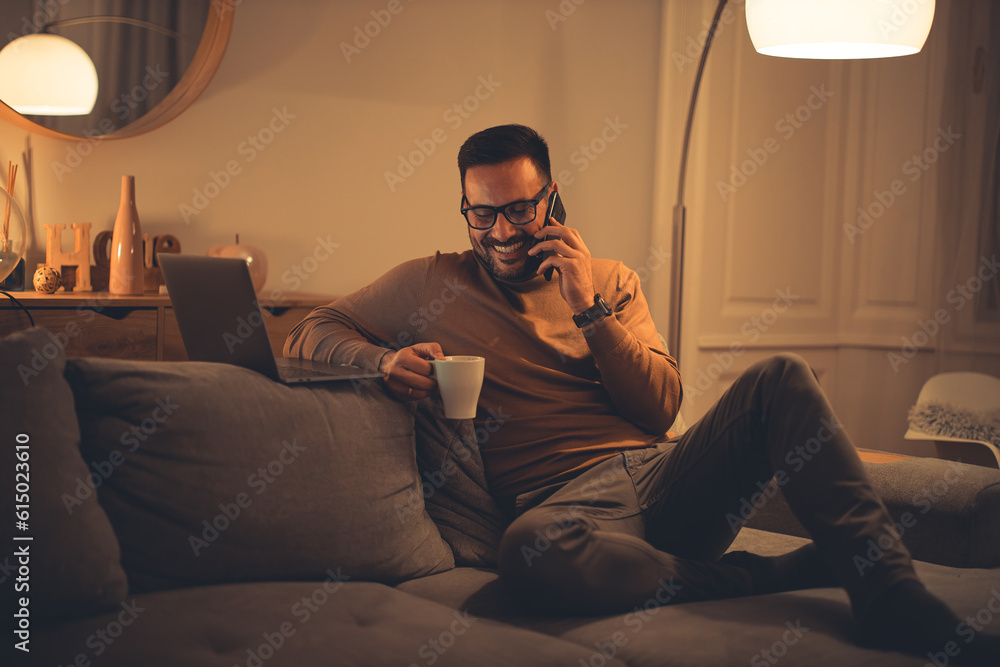 Smiling man having a phone call while sitting on the sofa, enjoying the evening. Smiling man having a phone call while sitting on the sofa, enjoying the evening.