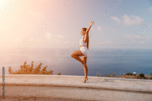 Fitness woman sea. A happy middle aged woman in white sportswear exercises morning outdoors in a park with a beach view. Female fitness pilates yoga routine concept. Healthy lifestyle.