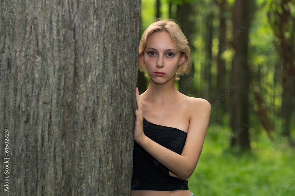 beautiful young woman next to the tree in the forest beautiful young woman next to the tree in the forest
