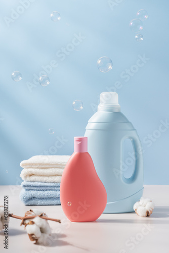 Quadro su tela Blue and pink plastic bottle of laundry detergent with cotton towels and branch of cotton in the background