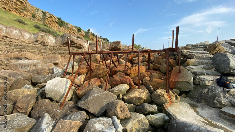 An abandoned rusty pier platform on the cliffs by the sea. Rusty steel beams, remnants of old sea pier An abandoned rusty pier platform on the cliffs by the sea. Rusty steel beams, remnants of old sea pier