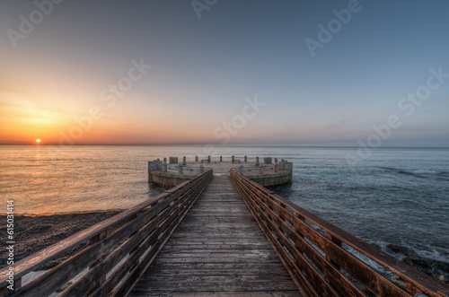 Fototapeta Naklejka Na Ścianę i Meble -  Morning on the pier and the roundabout overlooking the sea with the splendid colors of sunrise