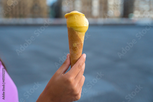 Hand of a young friend with a mango ice cream by the beach in summer vacation