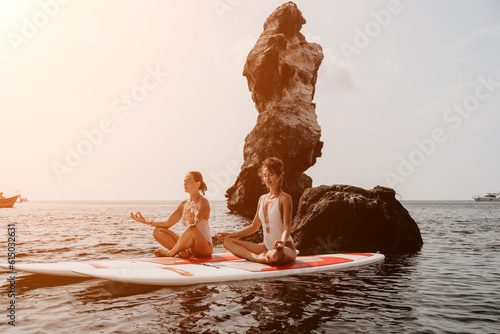 Woman sup yoga. Happy sporty woman practising yoga pilates on paddle sup surfboard. Female stretching doing workout on sea water. Modern individual female hipster outdoor summer sport activity.