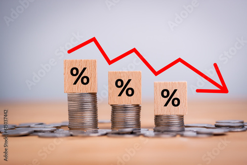 Fotografija Percentage sign on wooden cubes with Stack of coin bar chart and red graph trending downwards on white background