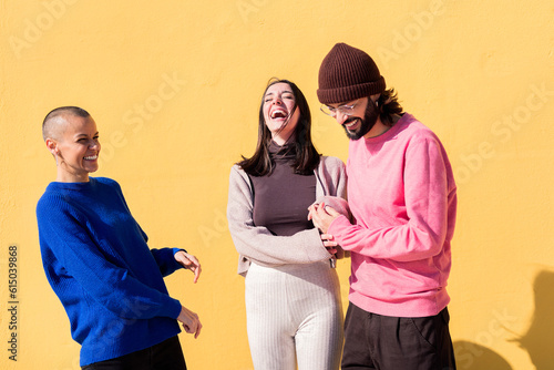 joyful young people laughing and having fun together on yellow background, concept of friendship and happiness