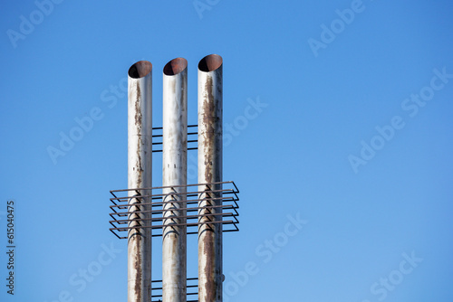  Three metal chimneys tower into the blue sky