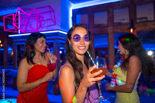 Portrait attractive smiling woman toasting and having fun with glass of alcohol in nightclub at night party