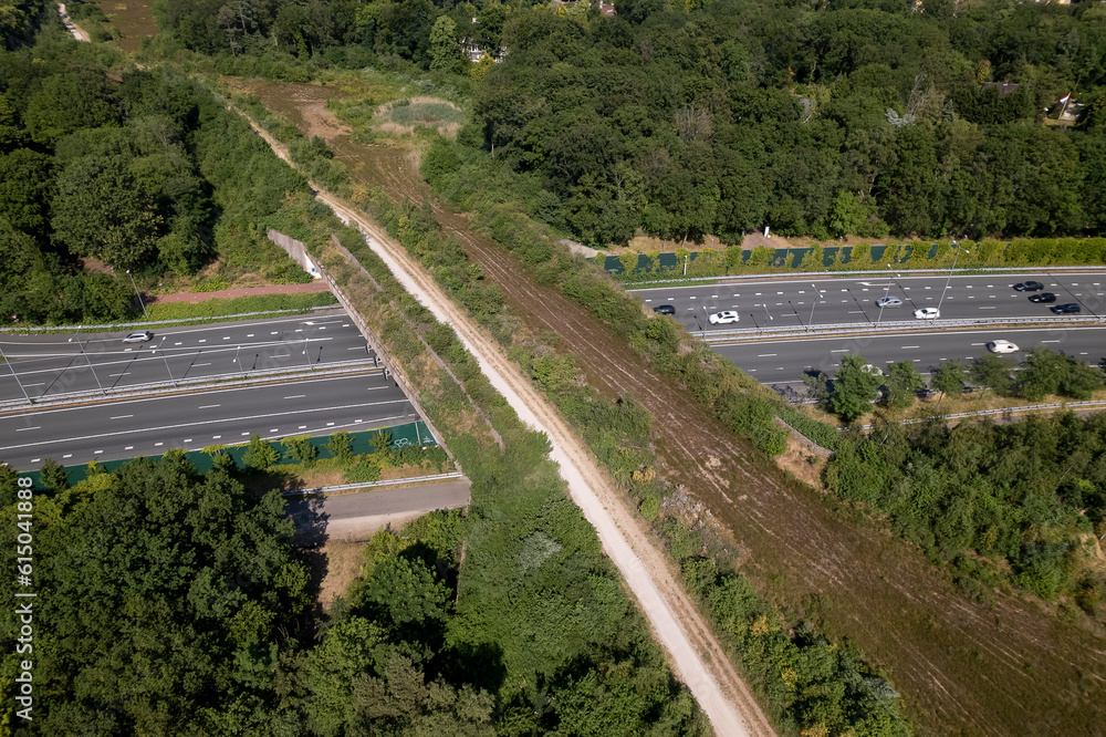 Interstate freeway with wildlife crossing green corridor bridge for animals to migrate between conservancy areas. Engineering aerial of environment nature reserve infrastructure eco passage.