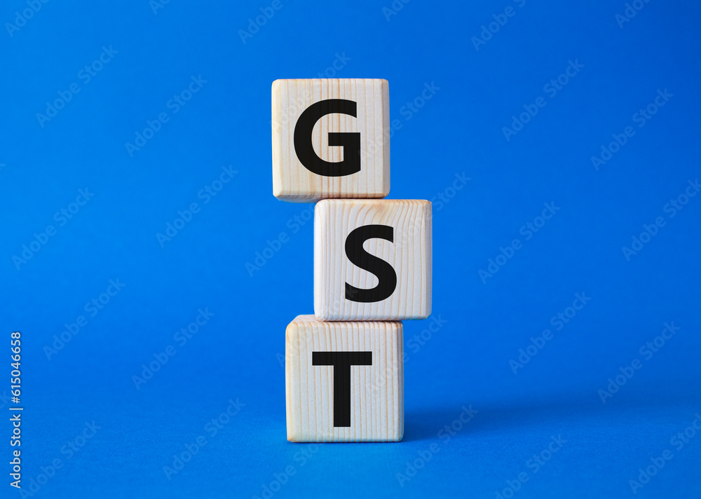 GST - Goods and Services Tax symbol. Concept word GST on wooden cubes. Beautiful blue background. Business and GST concept. Copy space. GST - Goods and Services Tax symbol. Concept word GST on wooden cubes. Beautiful blue background. Business and GST concept. Copy space.