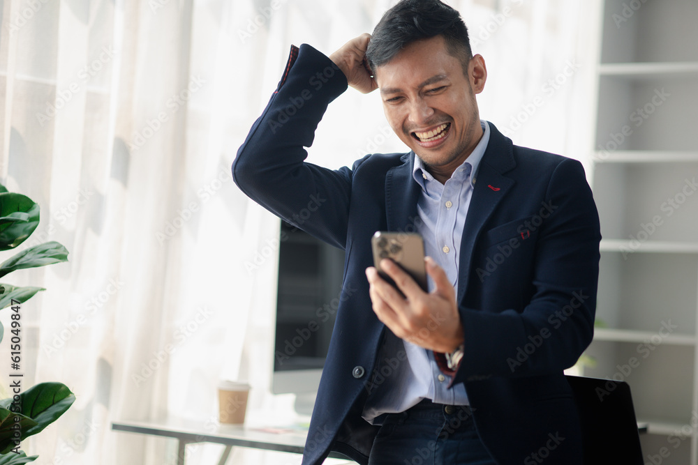Man holding mobile phone and celebrating, he is young businessman, modern business management, start-up company run by young people, modern entrepreneur with new ideas. to be a business leader. Man holding mobile phone and celebrating, he is young businessman, modern business management, start-up company run by young people, modern entrepreneur with new ideas. to be a business leader.