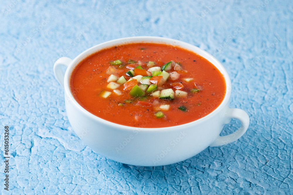 Traditional Spanish gazpacho soup in bowl on blue background Traditional Spanish gazpacho soup in bowl on blue background