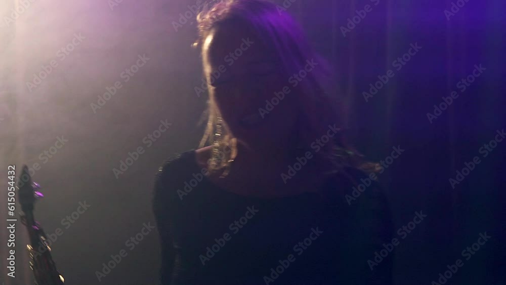 Blonde woman singing euphorically at a rock concert being illuminated by stage lights. Slow motion Blonde woman singing euphorically at a rock concert being illuminated by stage lights. Slow motion