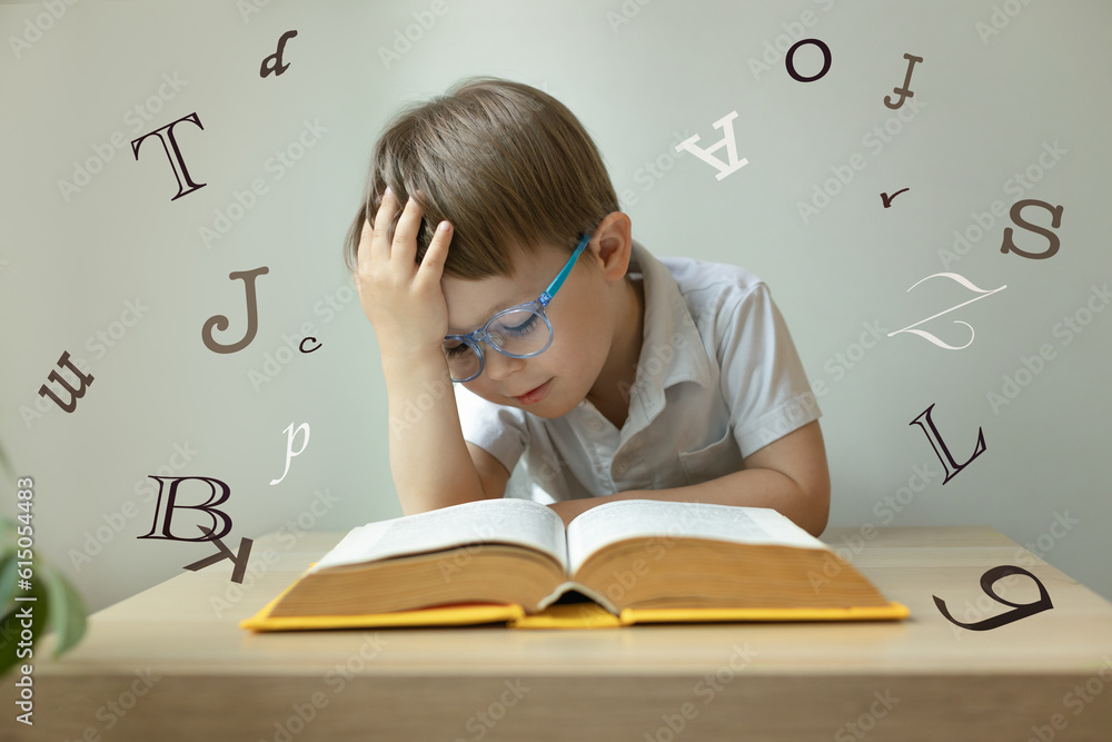 Cute little boy wearing glasses, open book in front of him, letters