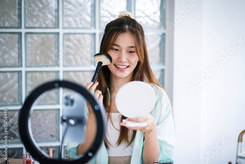Beauty influencer Asian girl makeup artist applying powder foundation by brush. Beauty influencer asian girl video online marketing live streaming .