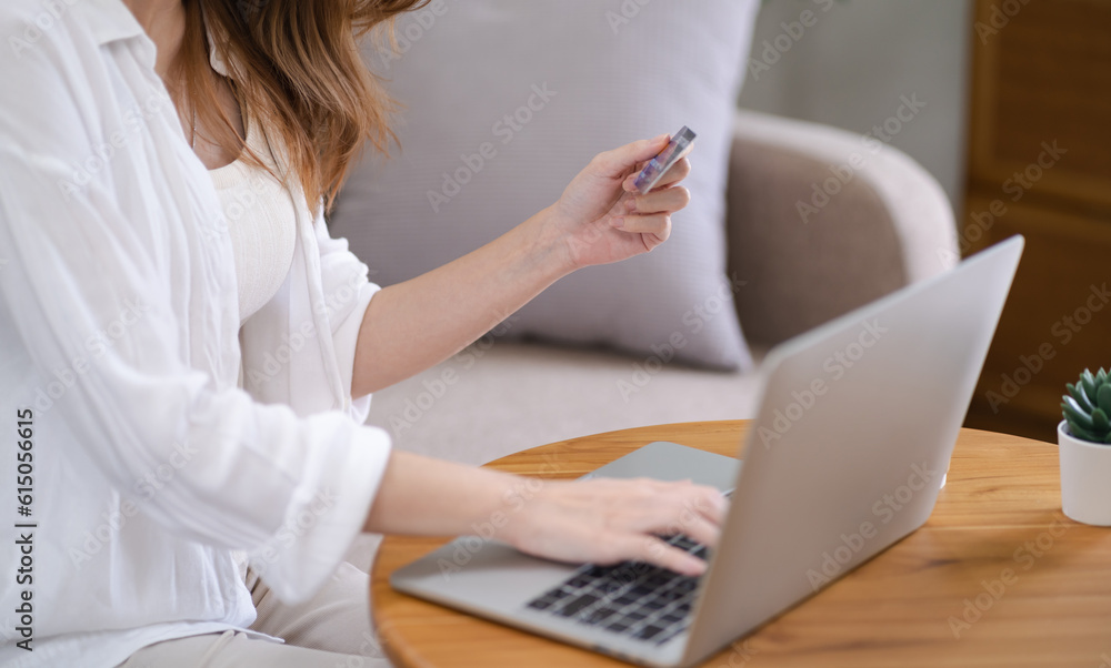 Fototapeta premium Woman shopping&nbsp;on laptop holding credit card for Internet online e-commerce shopping spending money Online shopping Mobile phone laptop technology concept