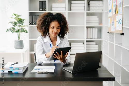 Business woman using tablet and laptop for doing math finance on an office desk, tax, report, accounting, statistics, and analytical research concept in office