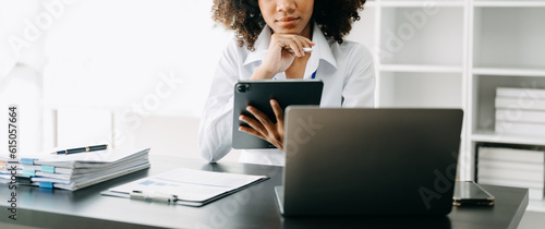 Business woman using tablet and laptop for doing math finance on an office desk, tax, report, accounting, statistics, and analytical research concept in office