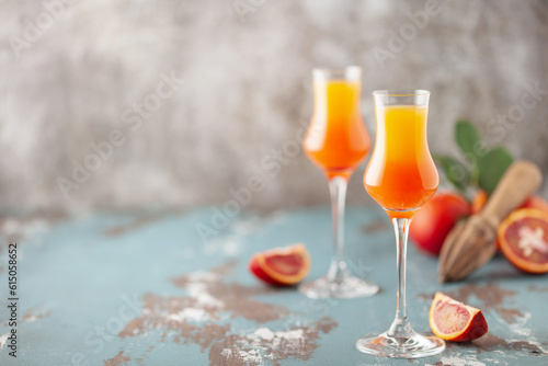 Принти на полотні Arancello in grappas wineglass, sweet Italian blood orange liqueur, traditional strong alcoholic drink and blood oranges on the light blue wooden background