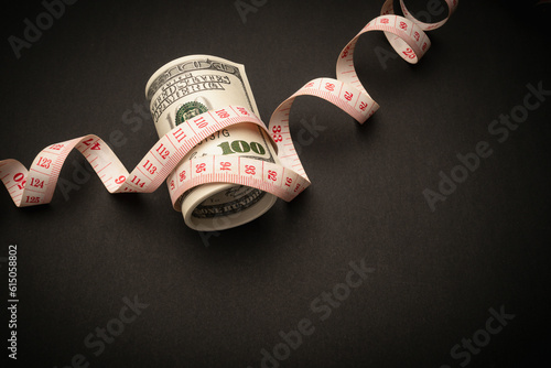 A tape measure was wrapped around a US dollar banknote on a black background. photo