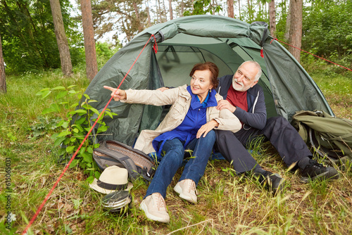 Woman pointing while sitting with man in tent
