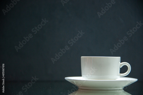Front view of white set of coffee cup and saucer on the left side on dark wave background with free space