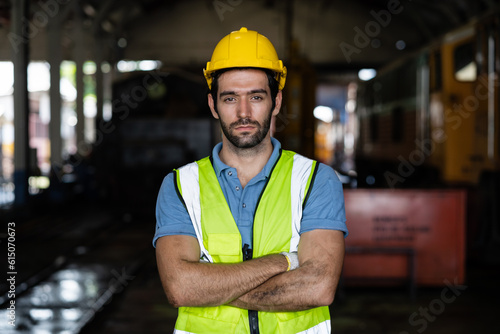Portrait of confident caucasian worker in factory, young engineer wearing vest and safety jacket looking at camera © KANGWANS