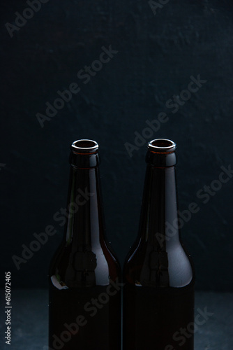 Vertical view of open glass bottles standing on table on dark wave background with free space