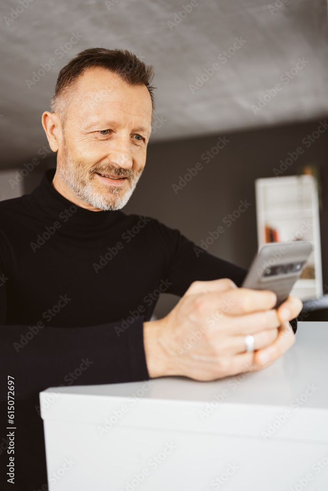 55-Year-Old Man with Turtleneck Looks Positively at His Smartphone 55-Year-Old Man with Turtleneck Looks Positively at His Smartphone