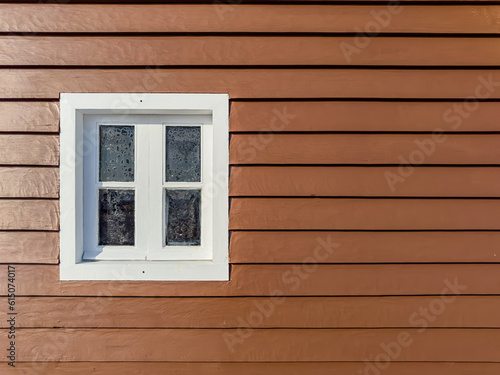 Brown wooden wall with white window. Close up.