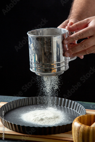 Half body shot of male chef sifting flour in the kitchen in close up view